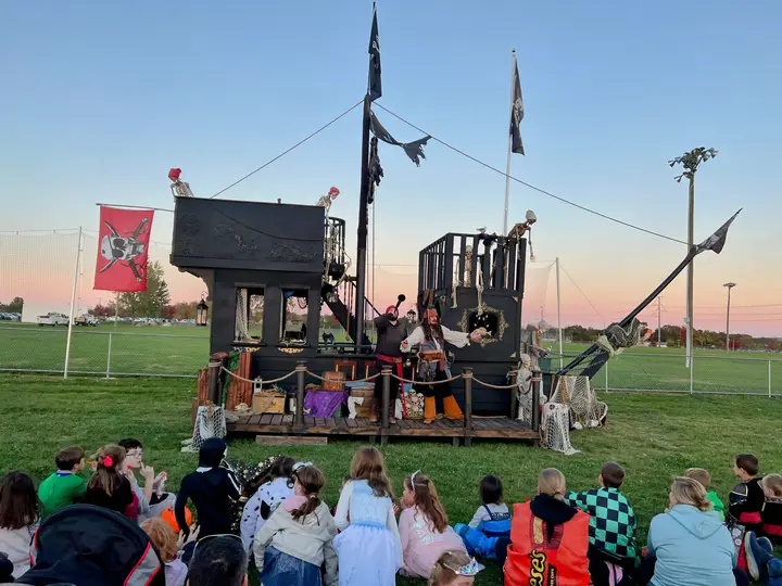 A pirate ship on wheels with a crowd watching